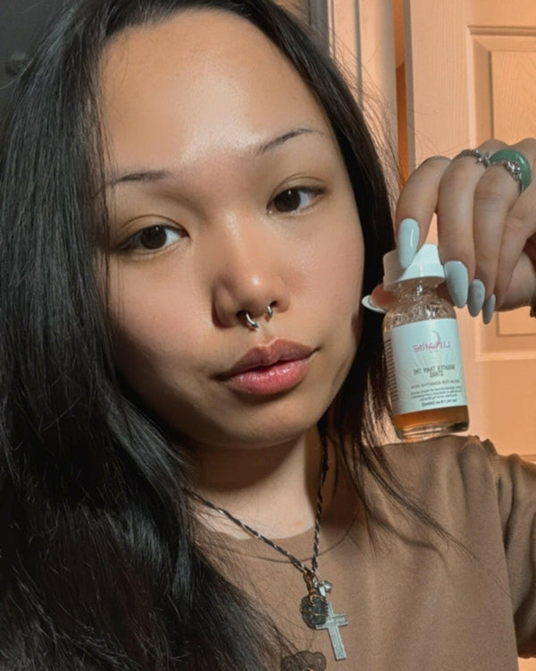 Woman holding a bottle of serum with a visible brand label.